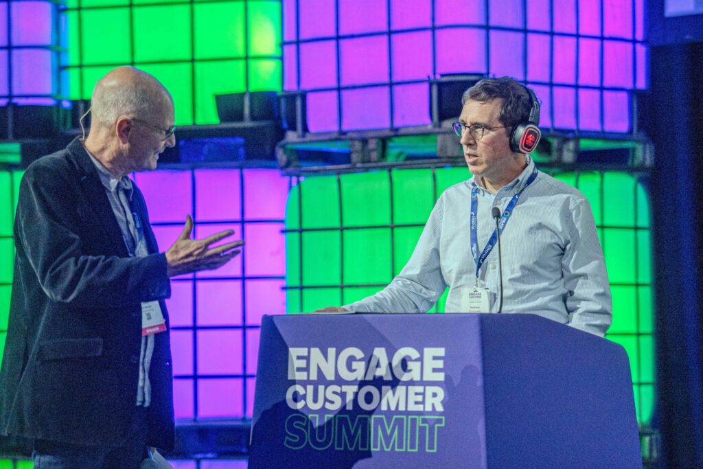 Martin Hill-Wilson in conversation with a speaker at the podium